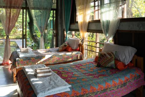 a bedroom with two beds and a window at Art House at Chiangdao - Lake House in Chiang Dao