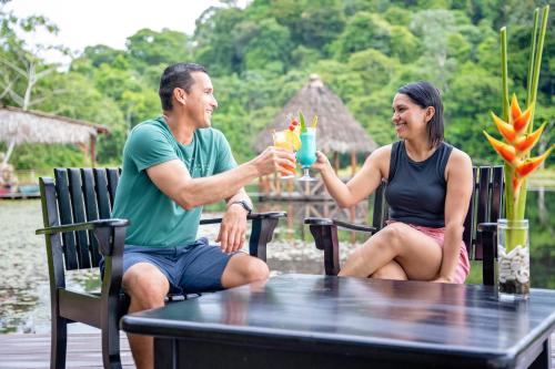 un homme et une femme assis à une table avec des boissons dans l'établissement Maquenque Ecolodge, à Boca Tapada