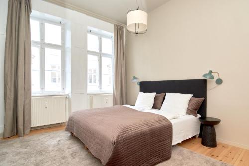 a bedroom with a bed with white sheets and windows at Scandinavian Style 3BR in Copenhagen City Centre in Copenhagen