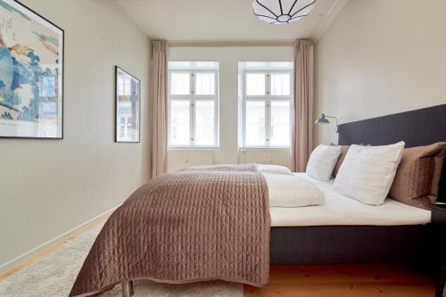 a bedroom with a large bed and two windows at Spacious 3B w Double Beds Copenhagen City Centre in Copenhagen