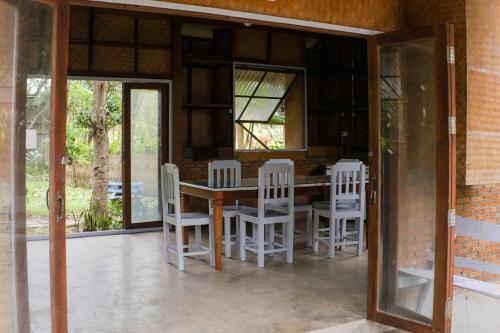 a dining room with a table and white chairs at Art House at Chiangdao - Lake House in Chiang Dao