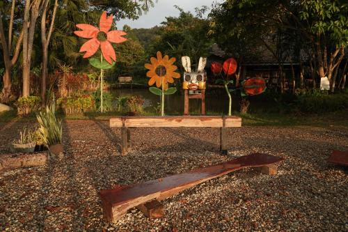 a bench with flowers on it in a garden at Art House at Chiangdao - Lake House in Chiang Dao