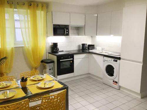 - une cuisine avec des placards blancs et un lave-linge/sèche-linge dans l'établissement Appartements Sun, parking, centre ville , proche Sanctuaires, à Lourdes