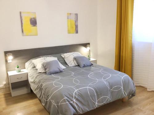 una camera da letto con un grande letto con due cuscini di Appartements Sun, parking, centre ville , proche Sanctuaires a Lourdes