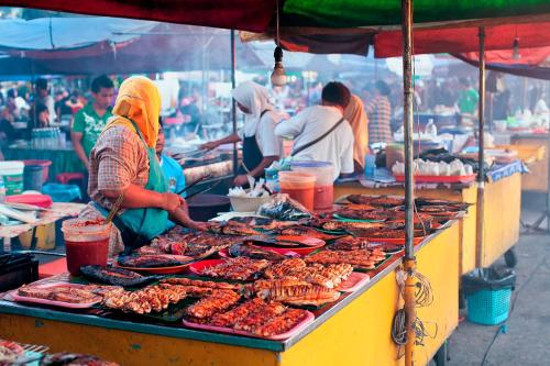 un grupo de personas preparando comida en un mercado en Jesselton Quay homestay with Free 1 parking by StayPlace en Kota Kinabalu