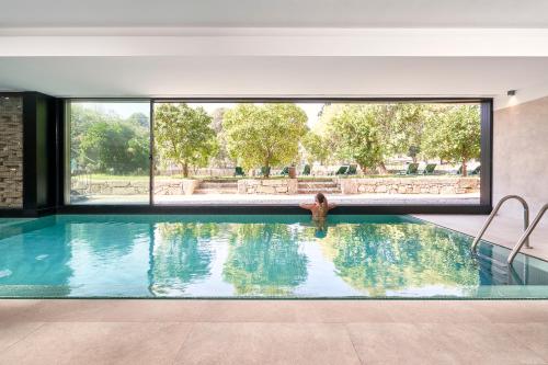 una donna in una piscina con una grande finestra di Ribeira Collection Hotel by Piamonte Hotels a Arcos de Valdevez