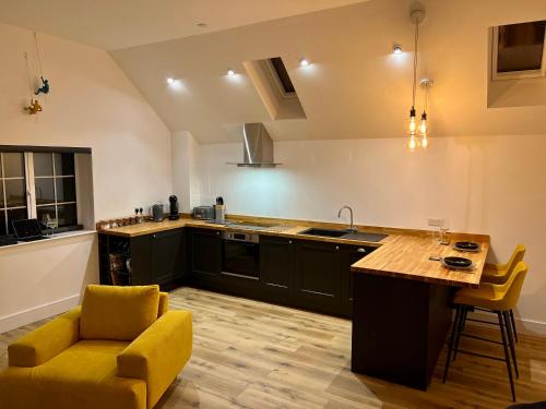 una cocina con armarios negros y una silla amarilla en Apple Tree Apartment, en Hensol