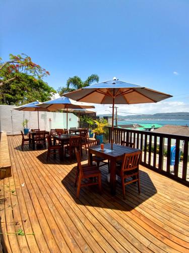 a deck with tables and chairs and umbrellas at Pousada Caminho do Mar in Bombinhas