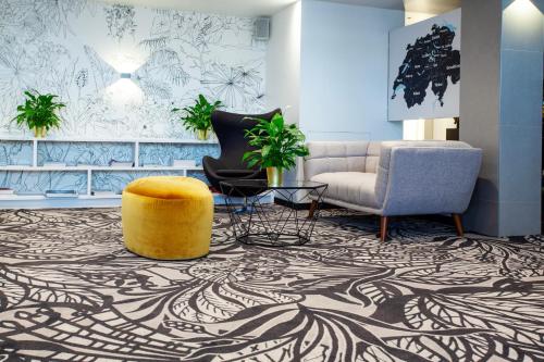 a lobby with a couch and a chair and a table at Mercure Biel in Biel
