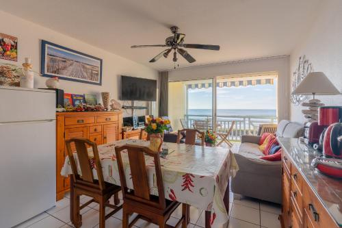une cuisine et une salle à manger avec une table et des chaises ainsi qu'une cuisine avec l'océan dans l'établissement Appartement Première ligne plage, à Mimizan