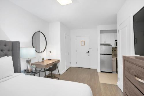 a bedroom with a bed and a desk and a kitchen at National at 888 Sixth Avenue - Furnished Apartments in New York