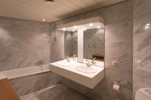 een badkamer met 2 wastafels, een spiegel en een bad bij Hello Zeeland - Appartement Loverendale 24 in Domburg