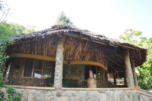 a small house with a thatched roof at Naiberi River Campsite & Resort in Eldoret