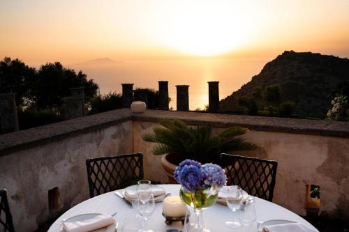 a table with wine glasses and a sunset in the background at Relais Villa Giusso in Vico Equense