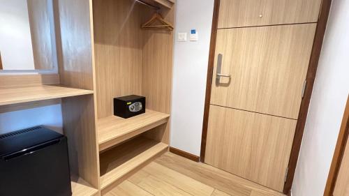 a small kitchen with wooden cabinets and a refrigerator at Aurora Boutique Hotel Imphal in Imphal