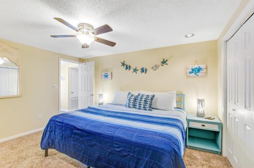 een slaapkamer met een blauw bed en een plafondventilator bij Tybee Southern Comfort in Tybee Island