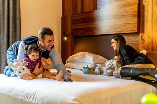 a man and a woman and two children sitting on a bed at Gasometer Urban Suites in Rome