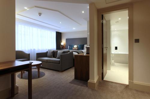 a living room with a couch and a bedroom at The Marble Arch Hotel, by Thistle in London