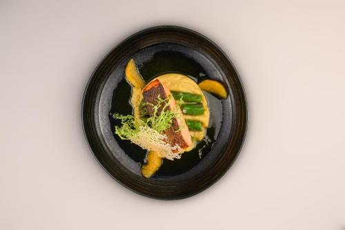 a black bowl of food with meat and vegetables at Inspira Liberdade Boutique Hotel in Lisbon