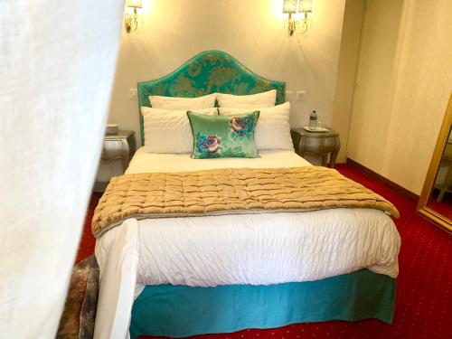 a bedroom with a large bed with a blue headboard at Le Chapeau Rouge in Lusignan