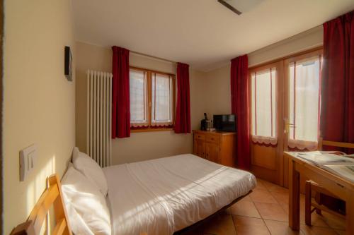 a small bedroom with a bed and red curtains at Walsertal Residence in Gressoney-la-Trinité