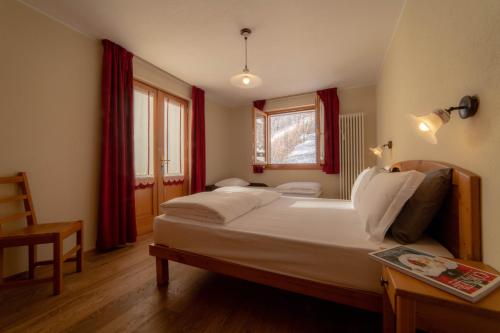 a bedroom with a bed and a chair and a window at Walsertal Residence in Gressoney-la-Trinité