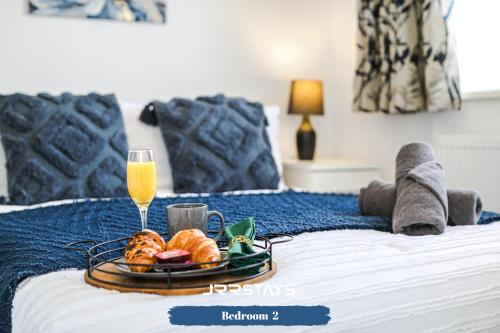 a tray of food and a glass of orange juice on a bed at Wolverhampton - Amazing 3 Bedroom, Sleeps 6, Wi-Fi - JRR Stays in Fallings Park