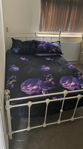 a bed with a black and purple comforter at Spacious Double Room in Leicester