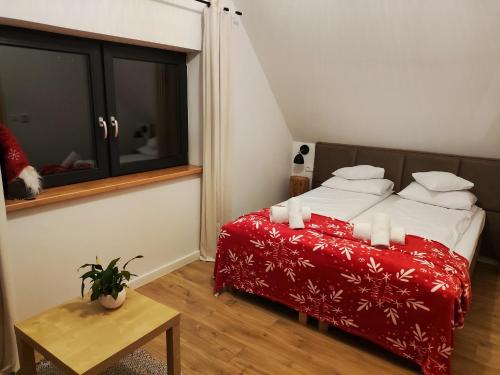 a bedroom with a bed with red sheets and white pillows at Przystanek Gorce in Nowy Targ