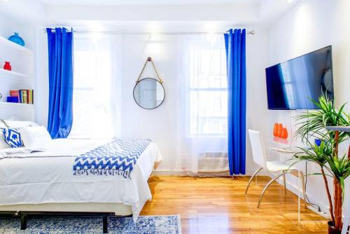 a bedroom with blue curtains and a bed and a tv at 62-3B Studio Prime UES Walk to Central Park in New York