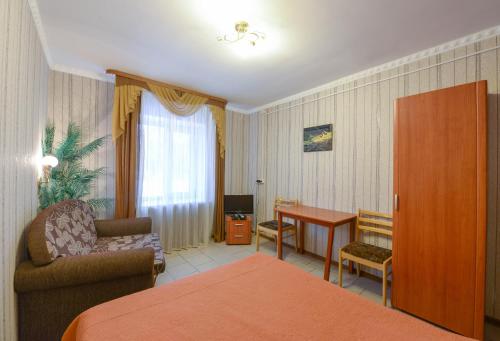 Habitación de hotel con cama, silla y escritorio. en Viktoria Hotel, en Cherepovets
