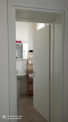 a bathroom with a sink and a toilet and a door at Porta Merlonia house in Forlì