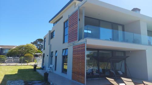 a house with glass windows and a yard at Hilltop Bayview Luxury Apartments in Plettenberg Bay