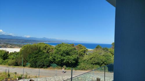 a person is playing tennis on a tennis court at Hilltop Bayview Luxury Apartments in Plettenberg Bay