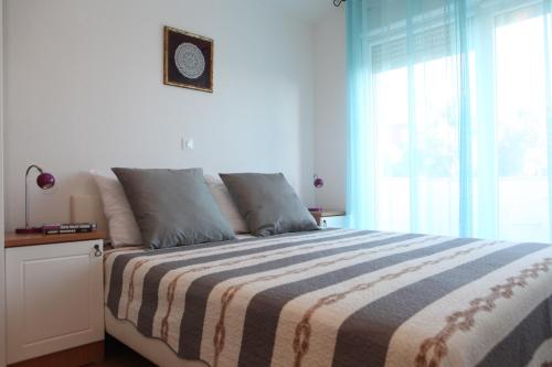 a bedroom with a bed with a striped blanket and a window at Apartments Sea View Kozino in Kožino