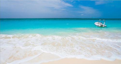 a boat in the ocean next to a beach at New Listing La Vista Azul Spacious 1 Bedroom Condo in Turtle Cove