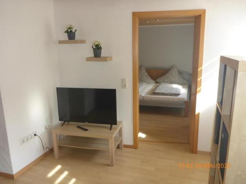 een woonkamer met een flatscreen-tv en een slaapkamer bij Ferienwohnung Christine in Heckendalheim