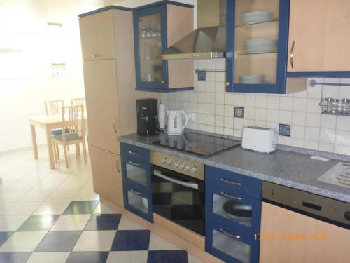 a kitchen with blue cabinets and a checkered floor at Ferienwohnung Christine in Heckendalheim