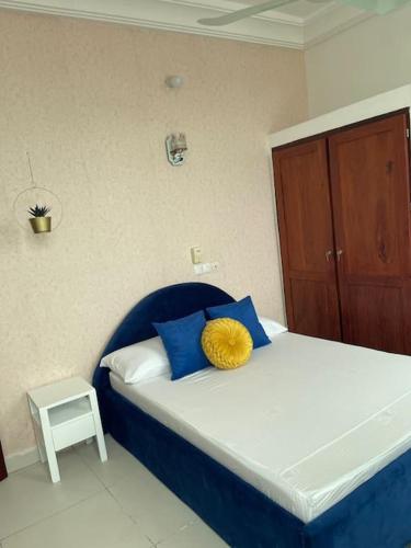 a bedroom with a bed with blue and yellow pillows at Superbe appartement cosy-chic in Cotonou