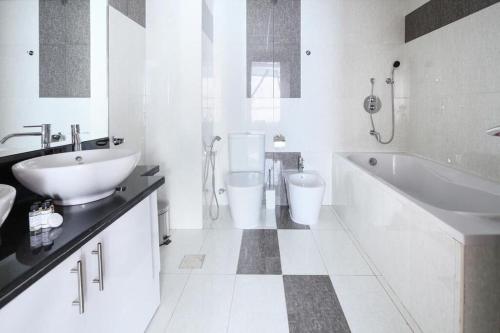 a white bathroom with a sink and a tub and a toilet at Key View - Park Towers in Dubai