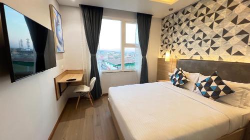 a bedroom with a bed and a desk and a window at Aurora Boutique Hotel Imphal in Imphal