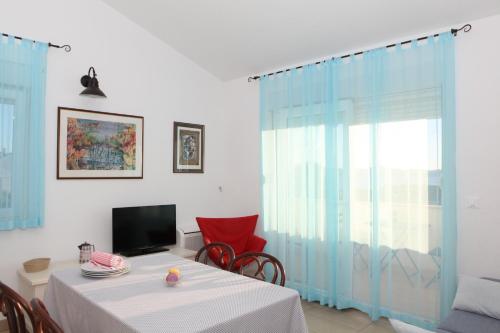 a dining room with a table and a television at Apartments Sea View Kozino in Kožino