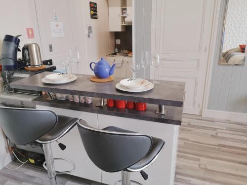 a kitchen with a counter with plates and wine glasses at VITTEL LOC'S - LE 216, classé 3 étoiles proche des Thermes et tous commerces in Vittel