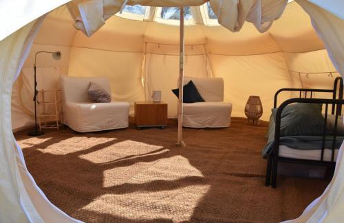 een tent met twee stoelen en een bed erin bij Stargazer Tent met sterrenuitzicht in Callantsoog