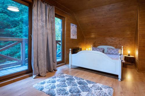 a bedroom with a white bed and a large window at TATRYSTAY RiverStone Chalets in Demanovska Dolina