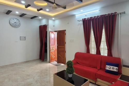 a living room with a red couch and a clock at Heaven Stay in Varkala