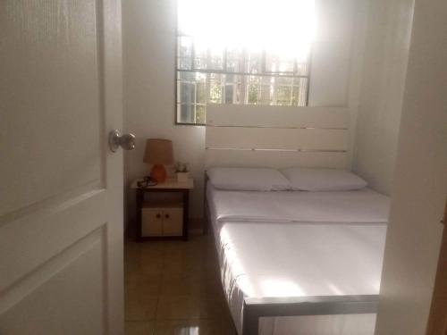 een kleine slaapkamer met 2 bedden en een raam bij Kendall Place Apartment in Cagayan de Oro