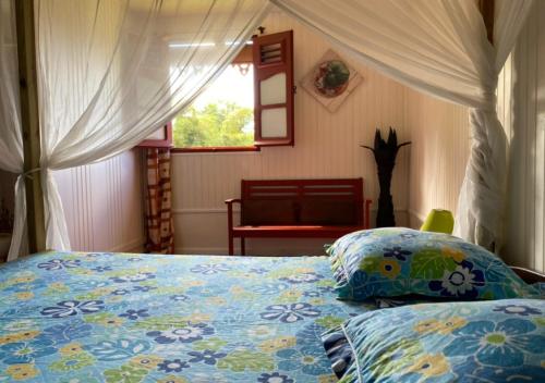 a bedroom with a bed with a blue comforter and a window at LE DOMAINE DE LA VALLEE in Le Morne Rouge