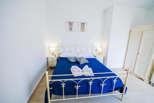 a bedroom with a blue bed with shoes on it at Cà del Re Holiday in Partinico