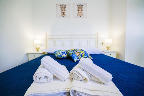 a blue bed with towels and pillows on it at Cà del Re Holiday in Partinico